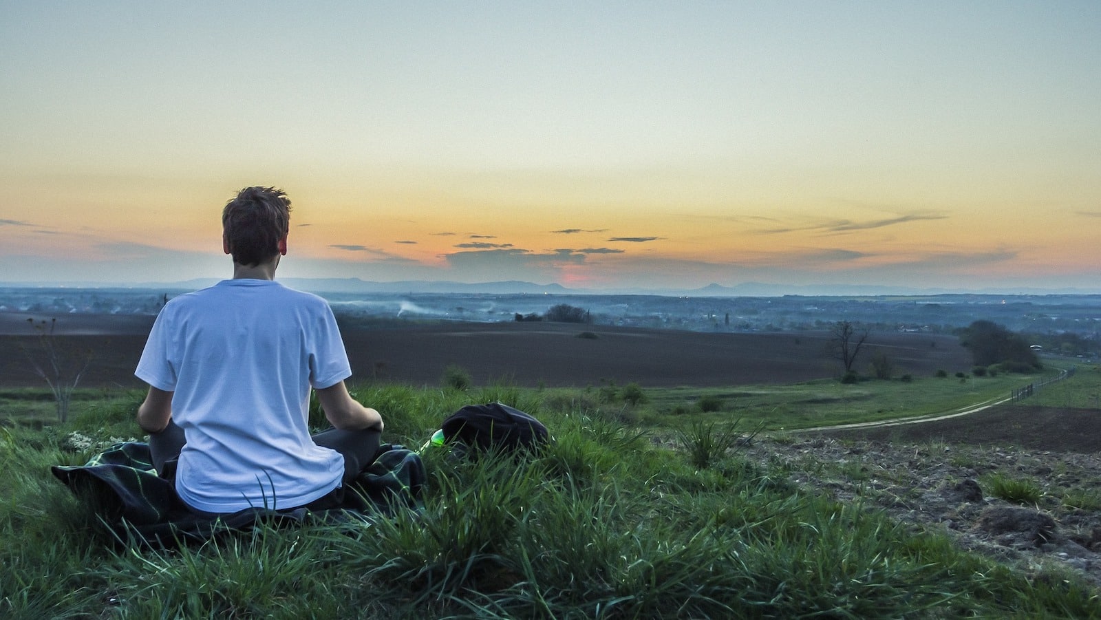 person meditating looking over landscape